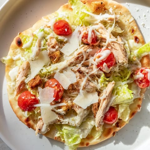Close-up of a delicious Chicken Caesar Flatbread, featuring grilled chicken and creamy Caesar dressing.