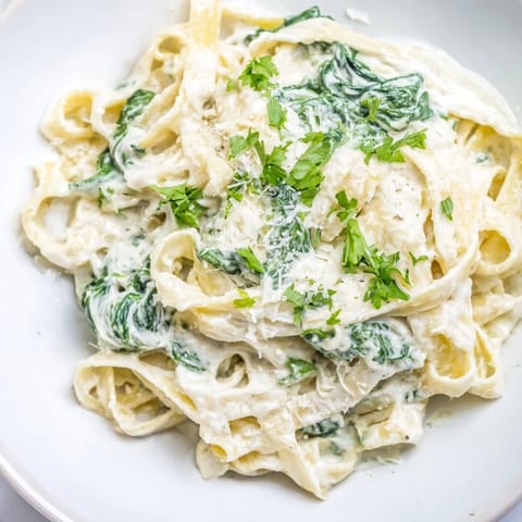 Steaming hot Creamy Spinach Fettuccine Alfredo, a comfort food classic with fresh spinach and Parmesan garnish.