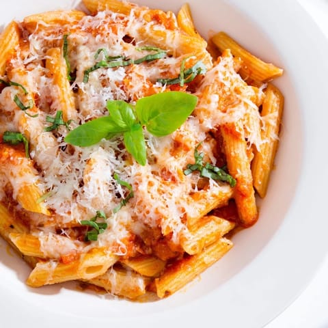 Golden, cheesy Baked Penne Arrabbiata, served with fresh basil, smells so delicious.