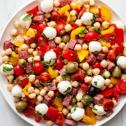 Frischer Crunchy Antipasto Chopped Salad mit knusprigem Gemüse, Salami und Mozzarella im Glas mit Dressing.